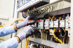 electrical-engineer-using-digital-multimeter-measuring-equipment-checking-electric-current-voltage-circuit-breaker-cable-wiring-system-main-power-distribution-board_545582-2692